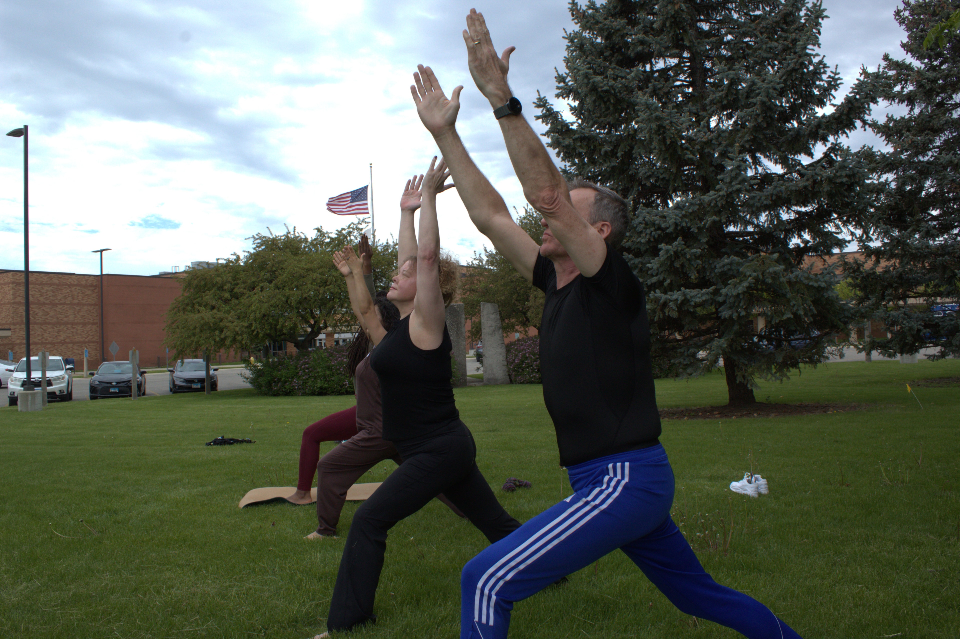 Roy leading an outdoor group yoga practice in Warrior One pose